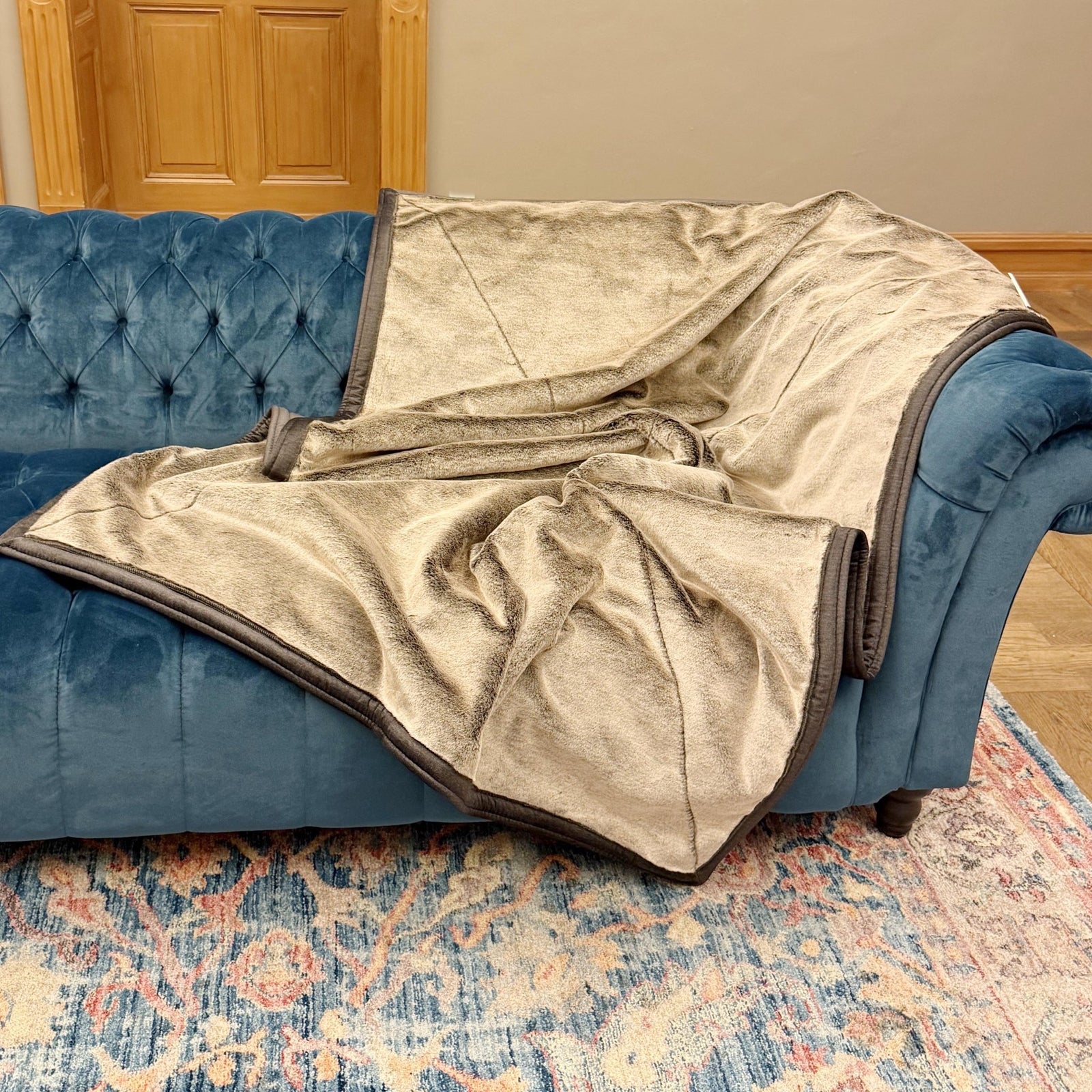 KONA CAVE®  luxurious weighted blanket with human-grade faux fur for people and pets.  Draped on a velvet sofa. washable faux fur silver tipped. 