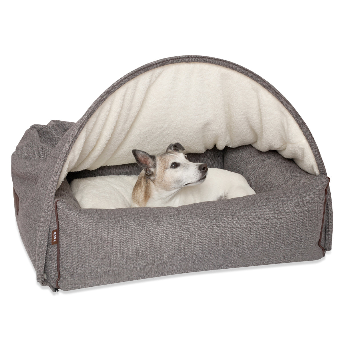 KONA CAVE® Jack Russell Terrier sitting in a big Snuggle Cave Bed by KONA CAVE®. Luxury hooded doggy den lined with super soft sherpa fleece. 