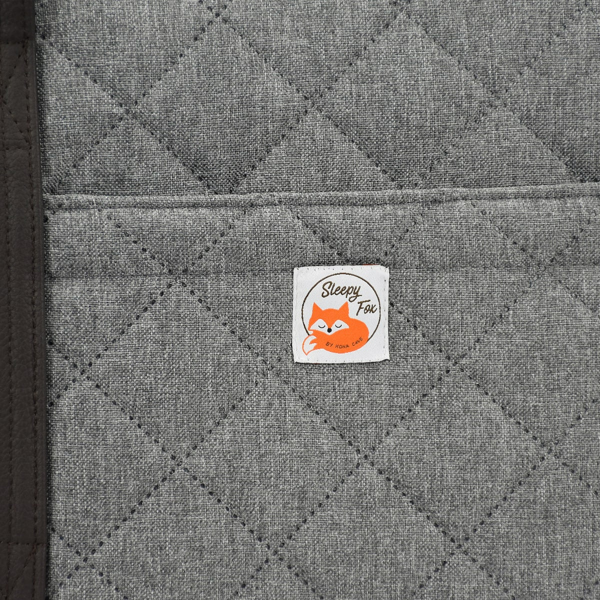 Portable dog bed. Folded, zips closed. Carried by long shoulder straps, handles. Ideal for restaurants, travel and parks. Close up of pocket