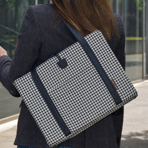 Woman carrying the KONA CAVE® Travel Dog Bed in Black and White Houndstooth on her shoulder in the city with her dog