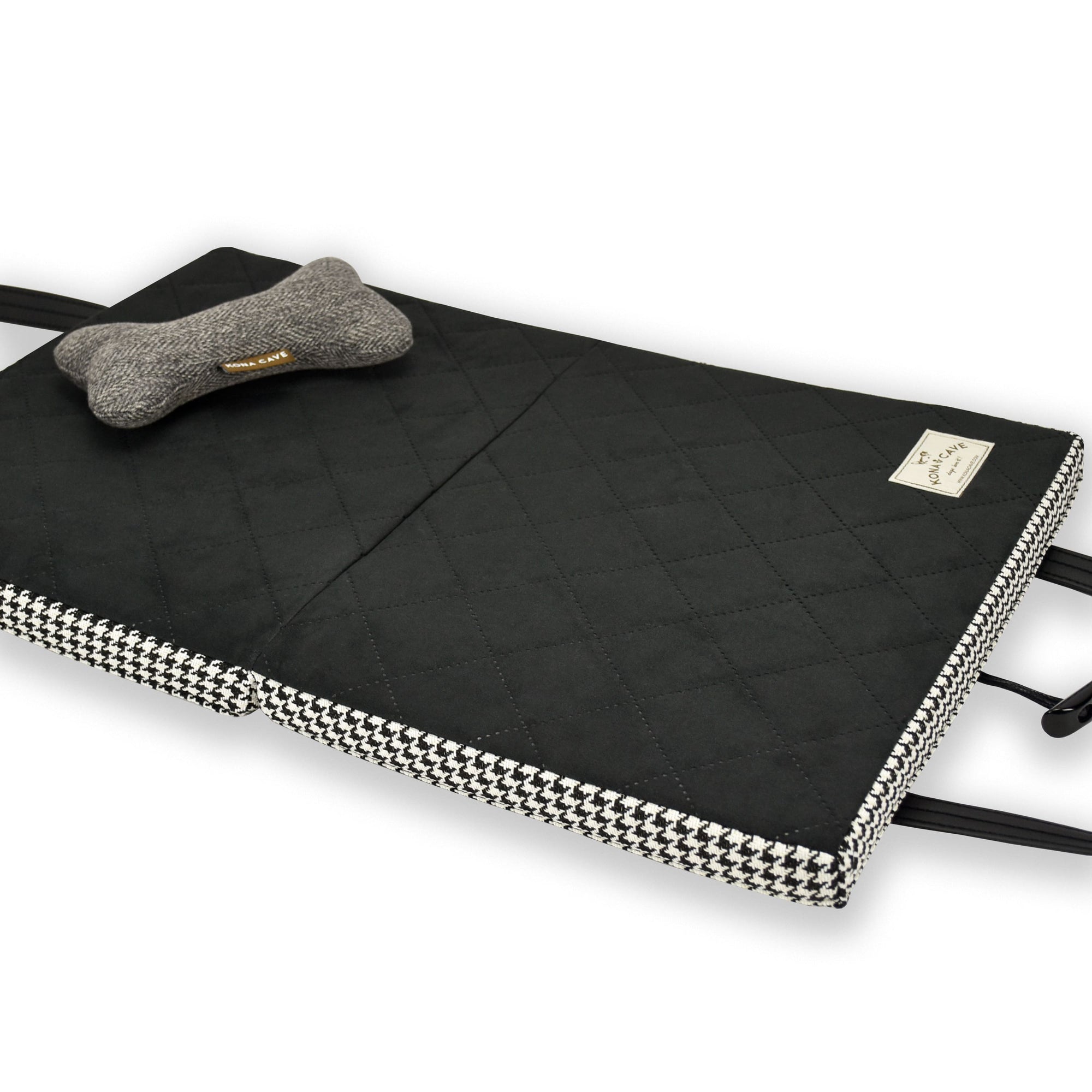 Open KONA CAVE® Travel Dog Bed in Black and White Houndstooth with Black Quilted Ultra-Suede Lining with a Toy Dog Bone on top. Padded restaurant dog bed.